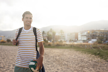 Young man with ball at the beach. Handsome man playing volleyball..