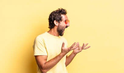 expressive crazy bearded man wearing sunglasses with a copy space against yellow wall