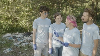 Wall Mural - Environmental volunteers getting ready to clean forest from piles of waste together, teamwork