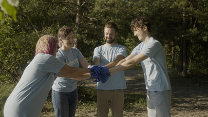 Wall Mural - Successful volunteer team stacking hands, ready to help save nature from waste