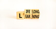 Lifelong learning symbol. Turned wooden cubes with concept words 'Lifelong learning' on a beautiful white background. Copy space. Business, educational and lifelong learning concept.