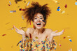 Leinwandbild Motiv Young happy satisfied excited fun surprised amazed woman 20s with culry hair in casual clothes tossing throwing confetti isolated on plain yellow background studio portrait. People lifestyle concept.