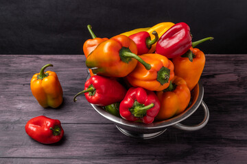 Wall Mural - Colorful sweet peppers in a colander on a wooden table