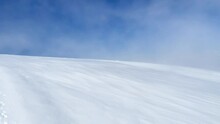 4K Running Clouds Moving Over The Snowy Desert. Strong Wind Weather During The Bright Blue Sky Sunny Day On The Dome Du Gouter 4304m Mount. Mont Blanc Ascending Route From The France.