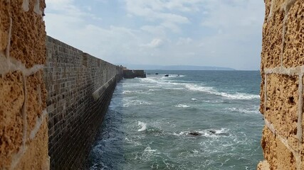 Poster - waves beat against a stone wall view from the window of an ancient fortress