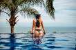 © Scopio - Back view of woman dipping in swimming pool