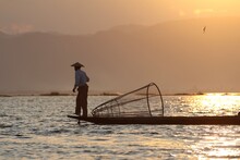 Man Fishing On Body O Water During Sunset