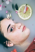 Portrait Of Girl's Face Submerged In Liquid With Flower And Lemon Wheel Floating