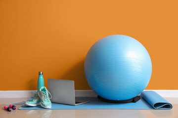 Canvas Print - Set of sports equipment and laptop on floor near color wall