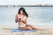 © Scopio - Woman sitting on the beach using smartphone
