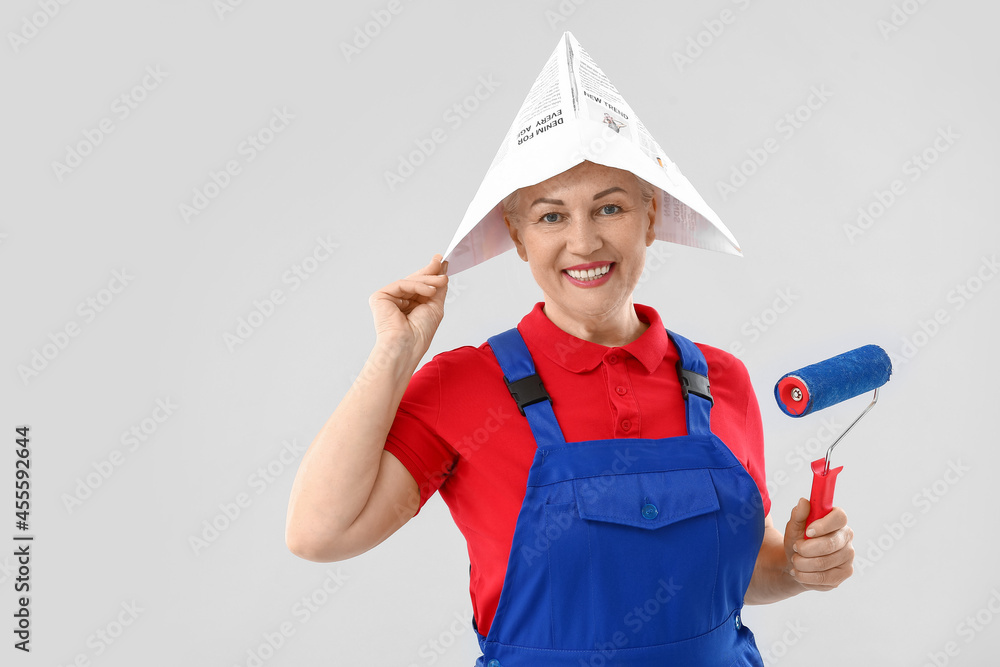 Female painter with roller brush on light background