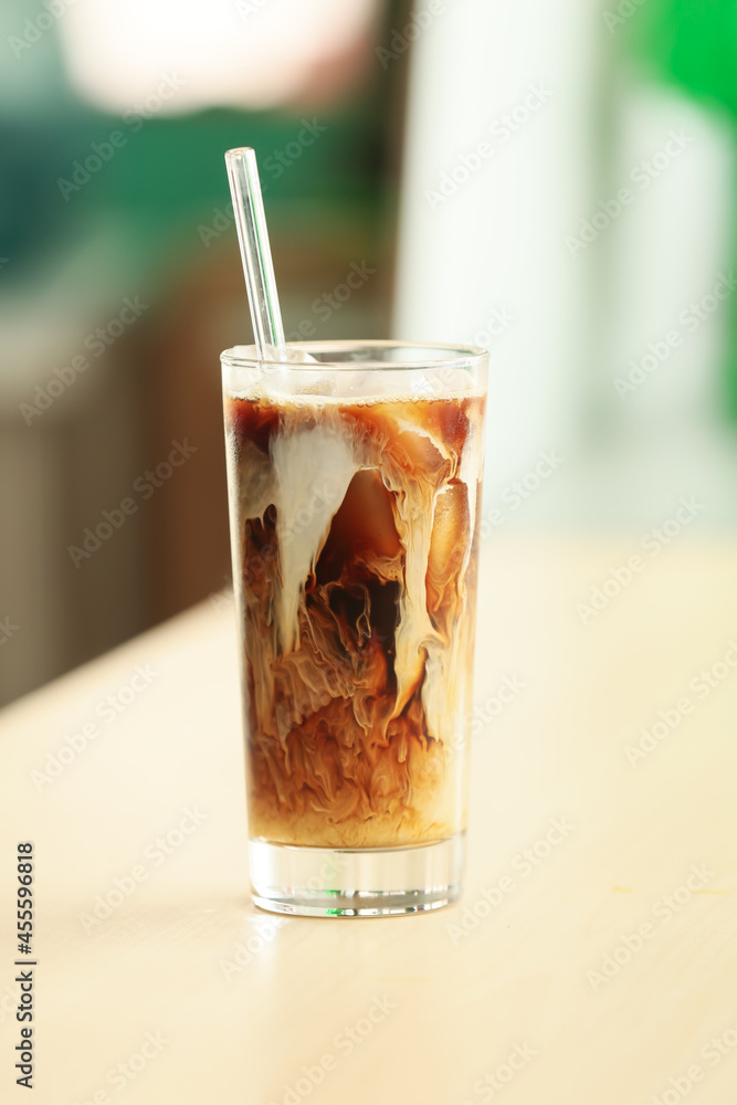 Glass of tasty ice coffee on table, closeup