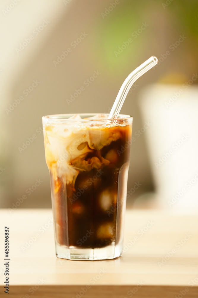Glass of tasty ice coffee on table, closeup