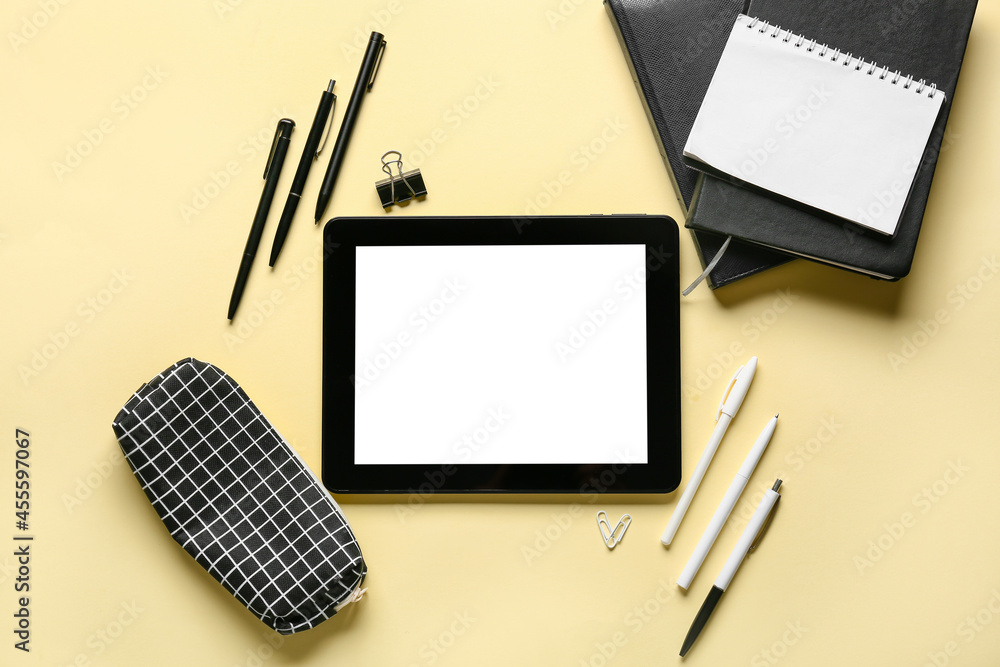 Blank tablet computer and stationery supplies on color background