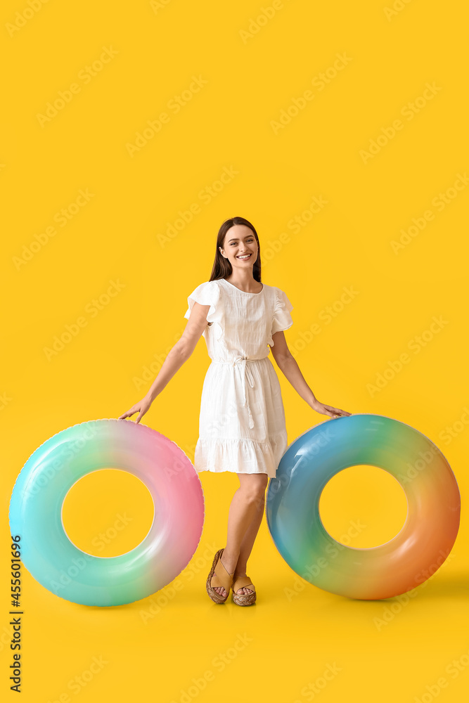 Young woman with inflatable rings on color background