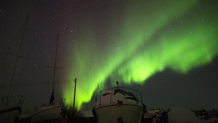 Wall Mural - Time Lapse Shot Of Sailboats Moored Over Snowy Landscape While Aurora In Sky At Night - British Columbia, Canada