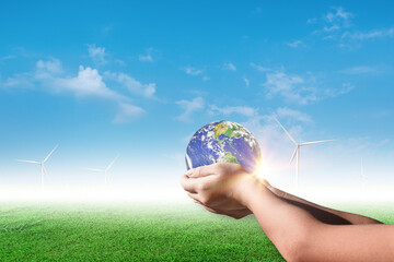 Canvas Print - hands holding earth, globe on wind turbine field against blue sky background. environment concept