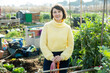 Portrait of female amateur gardener proud of her garden standing in homestead