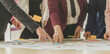 © Bangkok Click Studio - Group of unrecognizable businesswomen meeting together brainstorming at working desk, pointing fingers and analysis data chart and graph with self-confidence and full of knowledge exchange in team