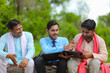 © PRASANNAPIX - young india bank officer completing paper work with farmers at home.