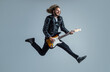 emotional bearded rock musician playing electric guitar in leather jacket and jumping, rocker