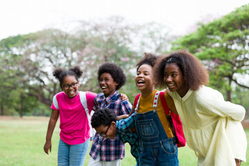 Wall Mural - Cheerful African American children standing in row straight and hugging shoulder. diverse black children hugging shoulder in the park. Successful and teamwork concept