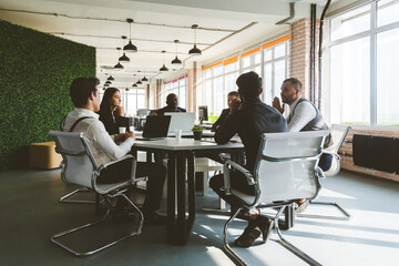 Sticker - Group of young business people working and communicating while sitting at the office desk together with colleagues sitting. business meeting