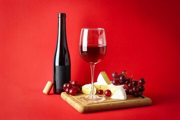 Wall Mural - Board with wine, cheese and grape on red background