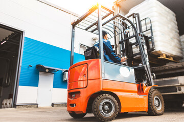 A man on a forklift works in a large warehouse, unloads bags of raw materials