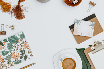 Flat lay Blogger workspace. Home office desk with tropical monstera leaf, cup of coffee, supplies,  notebook and pen. Flat lay, top view, copy space