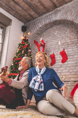 Wall Mural - Senior couple having fun celebrating Christmas at home