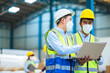 © SEVENNINE_79 - Team engineers and foreman wear a mask, hard hat, and vest. Standing, consult discuss industrial production management through data files with in mask factory. Employees working in the background.