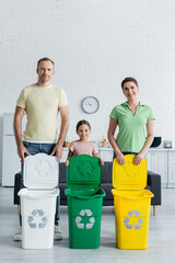 Wall Mural - Positive family with daughter standing near trash bins with recycle sign in kitchen