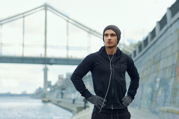 Young european runner standing at city quay