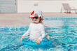 © Nadezhda - Little girl swimming in pool with blue water in swimwear with sun protection. Healthy and safe summer outdoor activities.