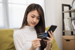 © Chanakon - Shopping online. Young asian teenage girl input the serial number of credit card to smartphone for shopping payment. Buy item online delivery at home. Smiling female feeling happy.
