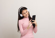 © Chanakon - Beautiful young asian women choose song and play music from smartphone connection with wireless headphone having fun in home. Teenage girl listen to the music enjoy relaxing on isolated background.