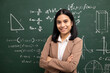 © Chanakon - Young asian teacher woman standing looking at camera and video conference with student. Female teacher training the mathematics in classroom blackboard from online course.