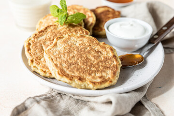 Wall Mural - Tasty oatmeal pancakes served with jam and natural yogurt on ceramic plate, light concrete background.