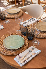 Mesa de restaurante turístico en la playa con copas, vasos, platos y cubertería completa