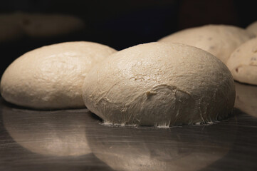 The uncooked round buns of dough are placed on a metal tray. Hamburger bun dough