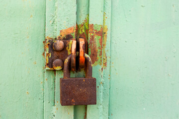 Wall Mural - rusty padlock on green gate background close up, property protection