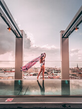 Woman In Monokini Standing Near Clear Glass Fence Beside Swimming Pool On Rooftop Of Skyscraper