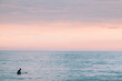 © RZCREATIVE/Stocksy - Lone surfer at sunset in the calm ocean.