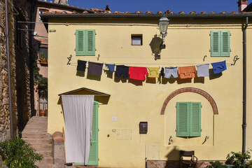 Wall Mural - Glimpse of the medieval village with washing lines on the façade of an old house in summer, Castagneto Carducci, Livorno, Tuscany, Italy