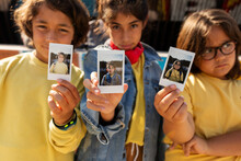 Kids Showing At Camera Their Instant Photo
