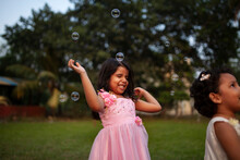 Little Indian Girls Playing With Soap Bubbles In A Park
