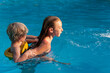 © Tytia Habing/Stocksy - Girl Carrying a Little Boy in the Pool