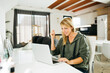 © Jordi Salas - Middle age smiling blonde woman using a laptop and having a video call in a livingroom