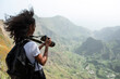 © David Prado/Stocksy - Beautiful black woman with camera taking photos